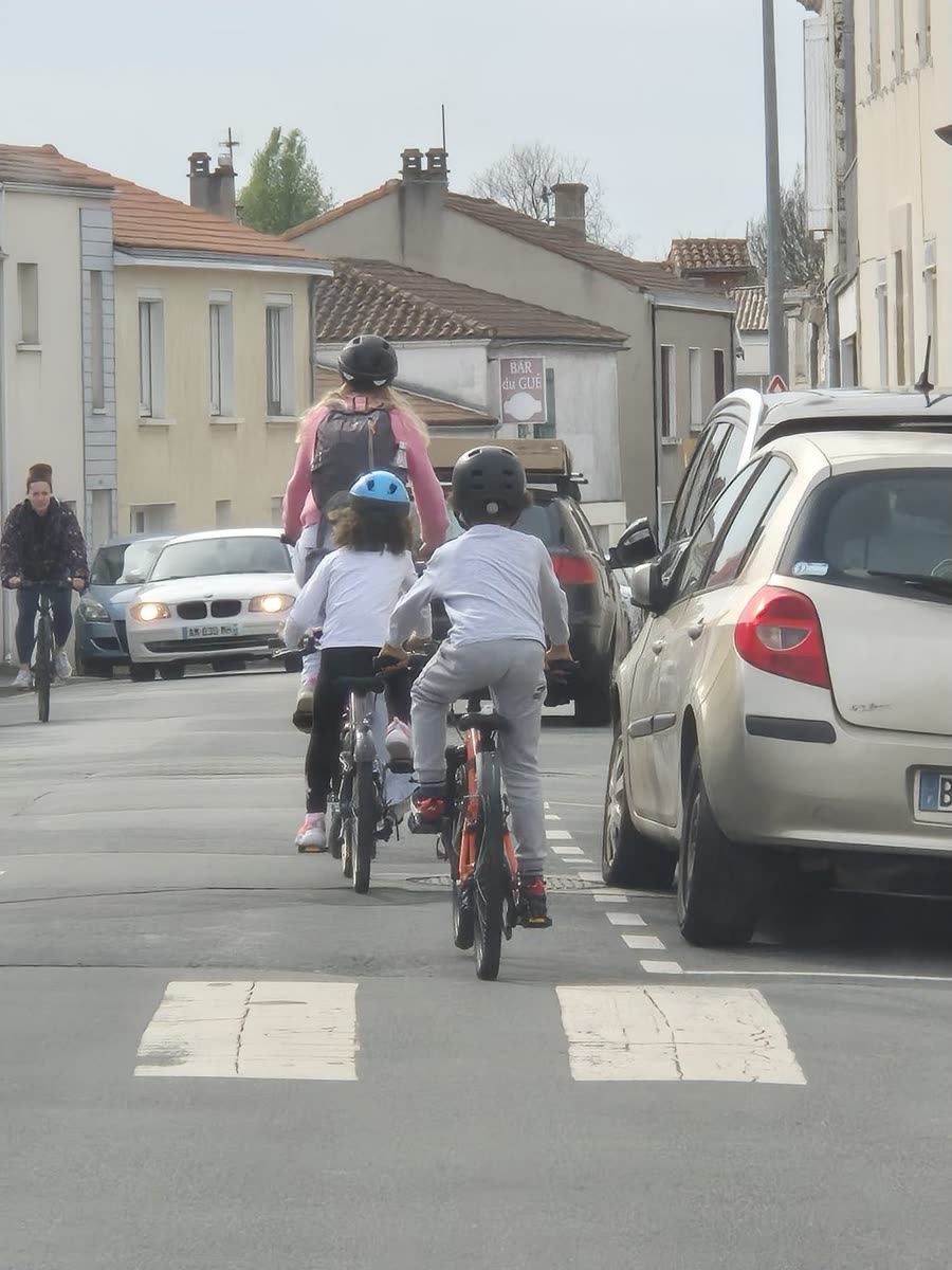 Deux enfants à vélo dans la rue Marius-Lacroix entre des voitures qui se croisent — situation actuelle dans la portion non encore réaménagée