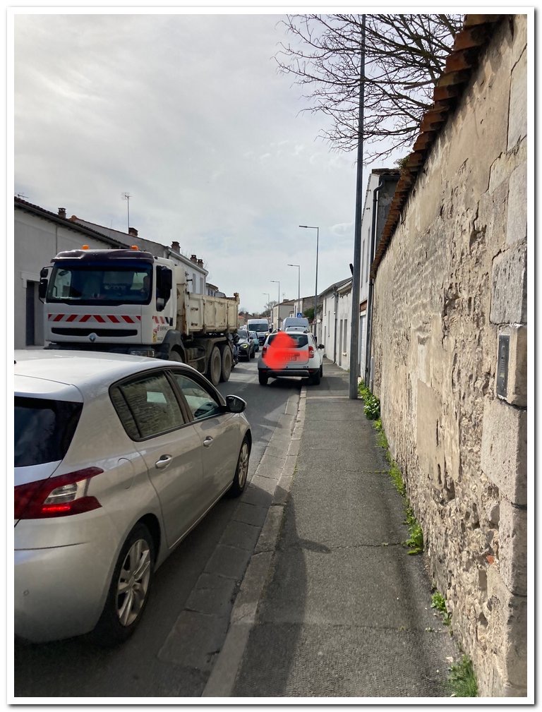 Camion benne croisant des voitures, file de véhicules à l'arrêt sur la rue Marius-Lacroix