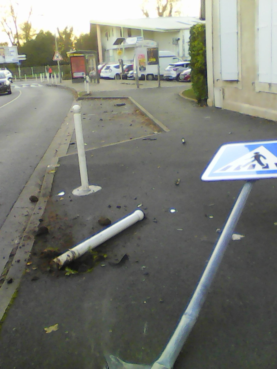 Panneau de signalisation de passage piéton arraché et couché au sol près d'un arrêt de bus, rue Marius-Lacroix