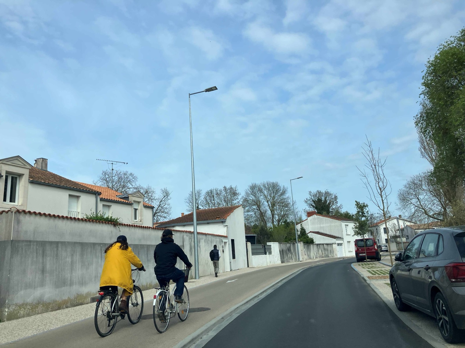Deux cyclistes circulant sur la piste cyclable bidirectionnelle de la rue Marius-Lacroix après la phase 1, chaussée refaite et arbres plantés